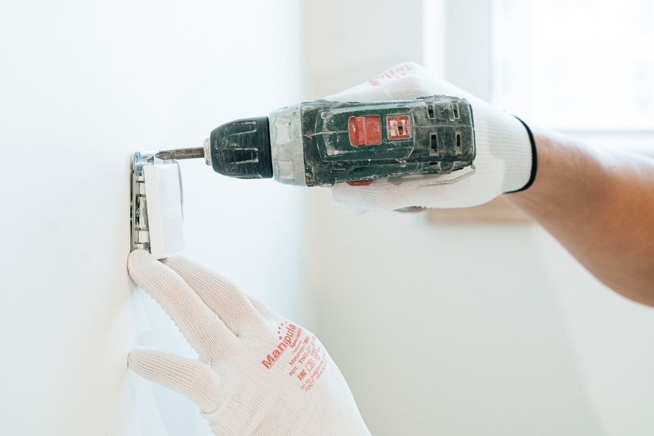 Electrician installing and repairing a wall outlet in a Boca Raton, FL residence